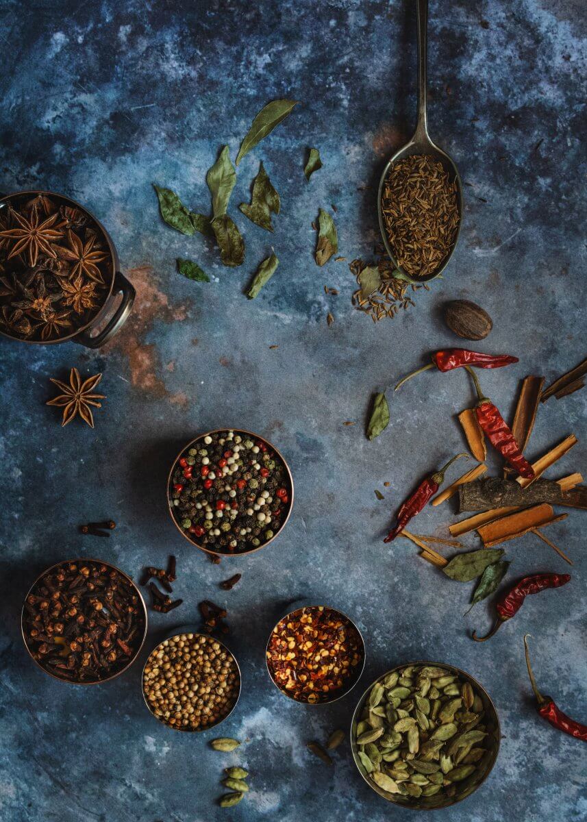 spoons and pots with a variety of whole spices food photography for Mandira's Kitchen
