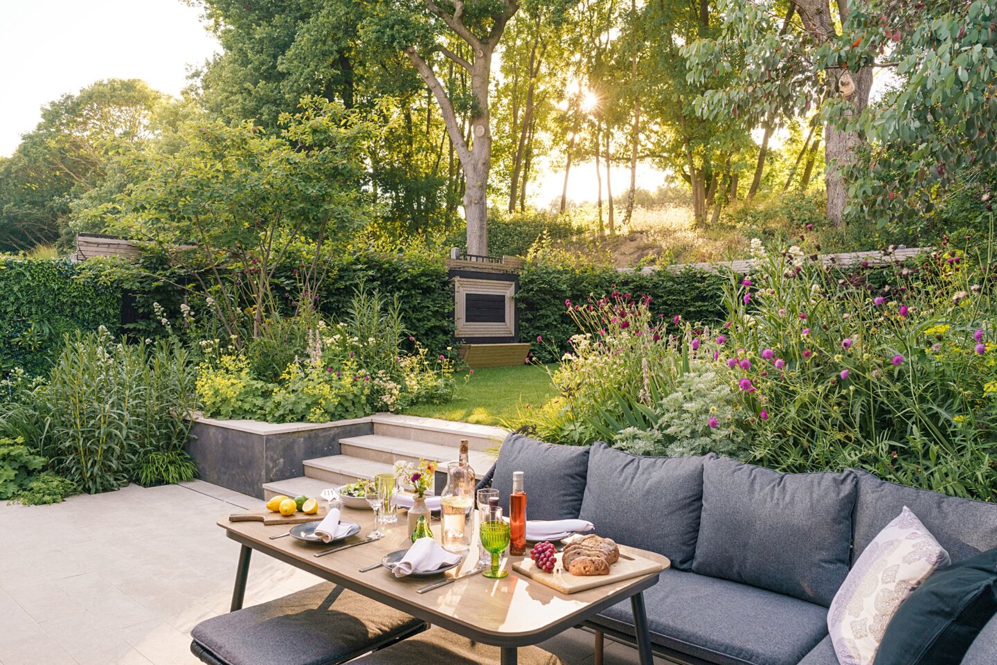 Example of compact family garden with raised lawn, seating and table area ready for dining