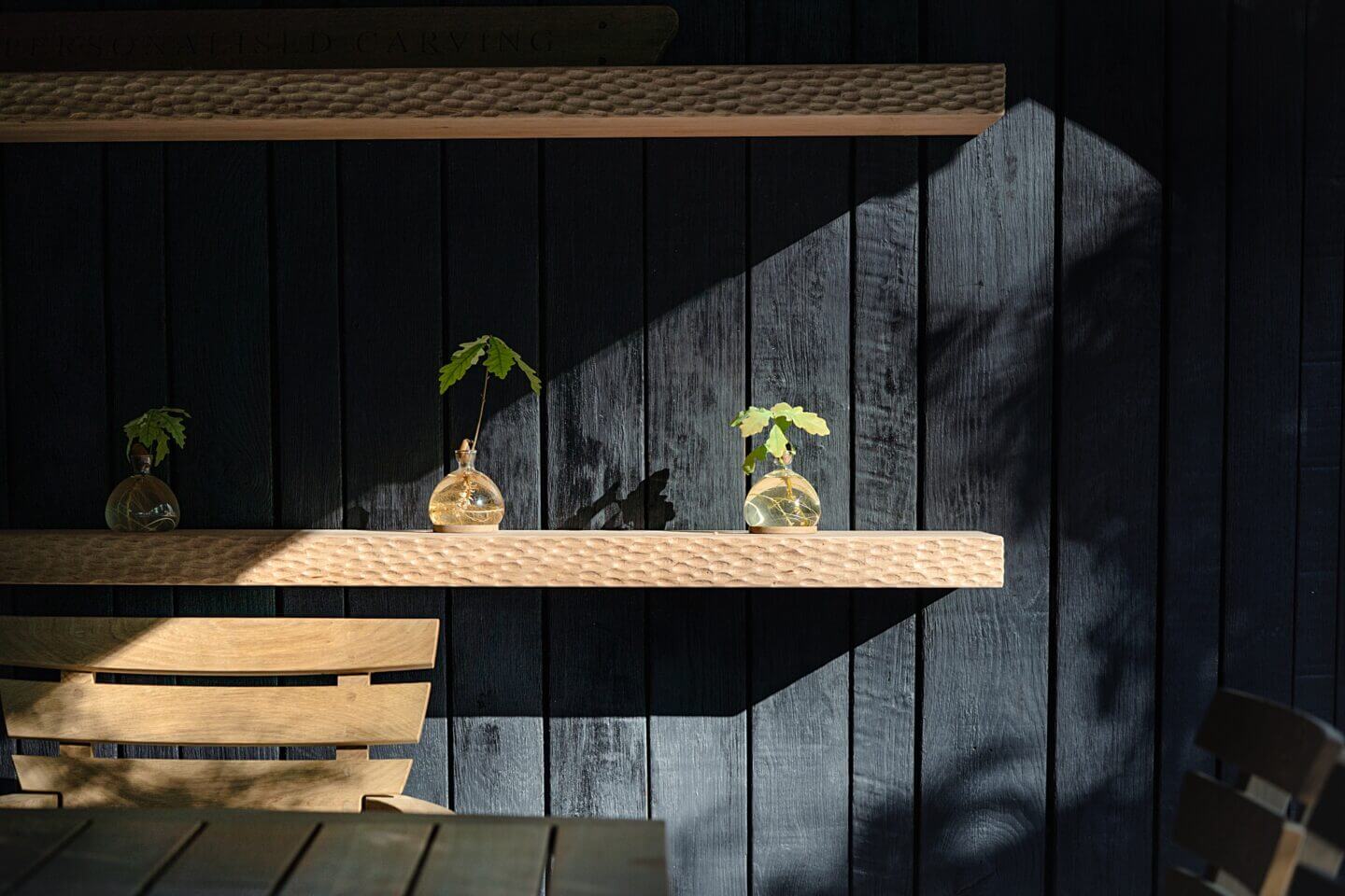 Sunlight highlights acorn vases on an oak beam by Oli Carter